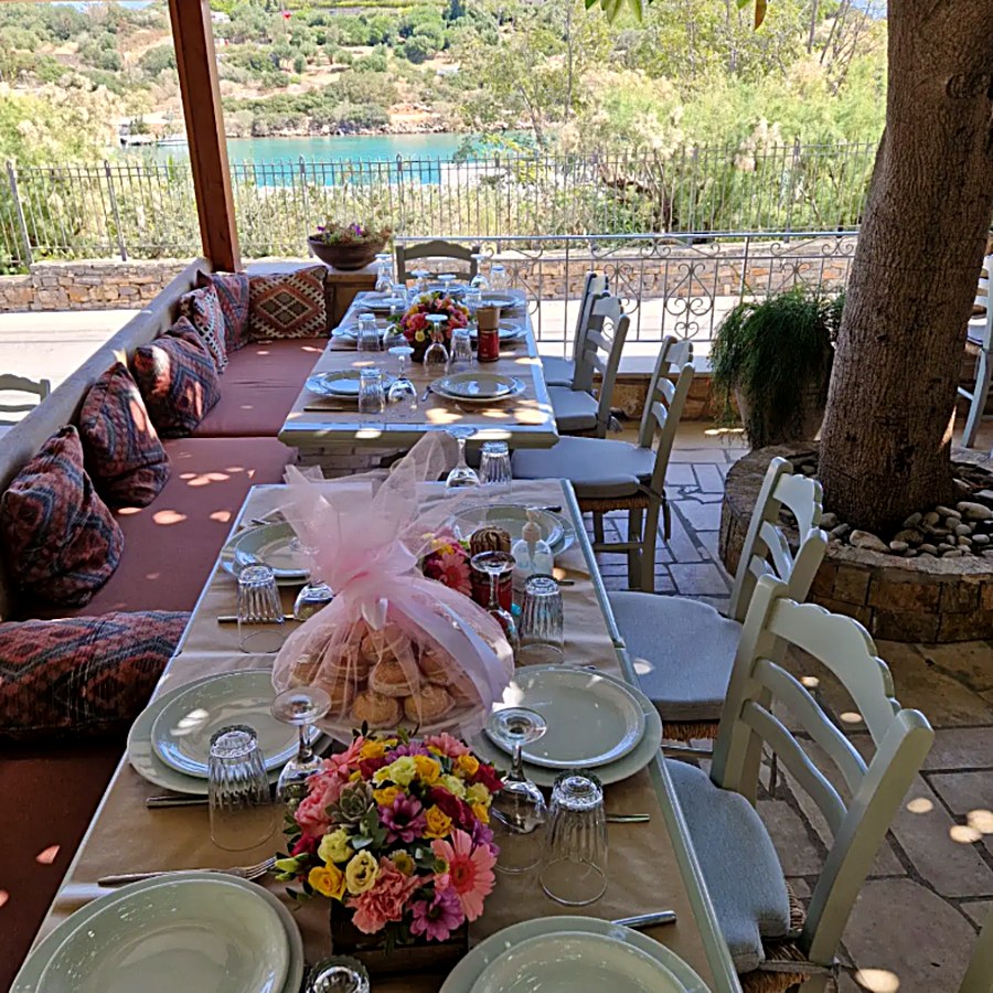 A long table set for a celebration on the Kri Kri terrace, flowers and the bay behind
