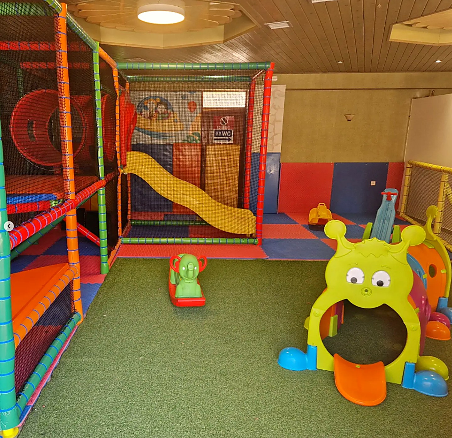 The Kri Kri playroom, soft-play frame, slide and ride-on toys on the green mat
